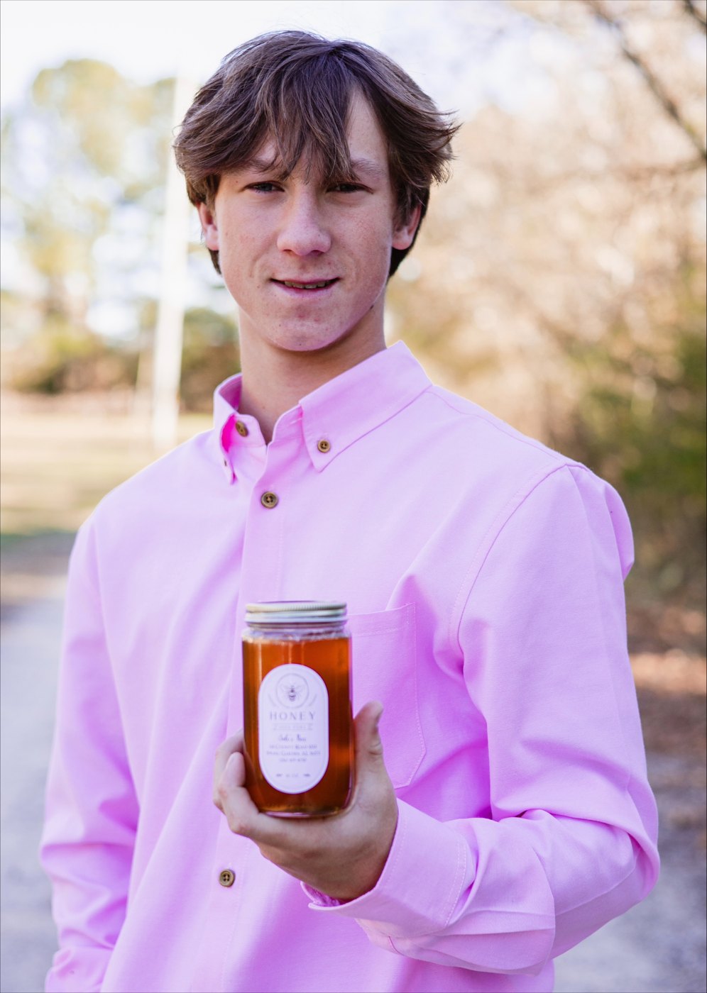 Jude Kiser holding a jar of Jude's Bees honey