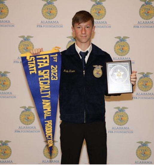 Jude holding his 1st place 2023 FFA State Specialty Animal Production pennant and plaque