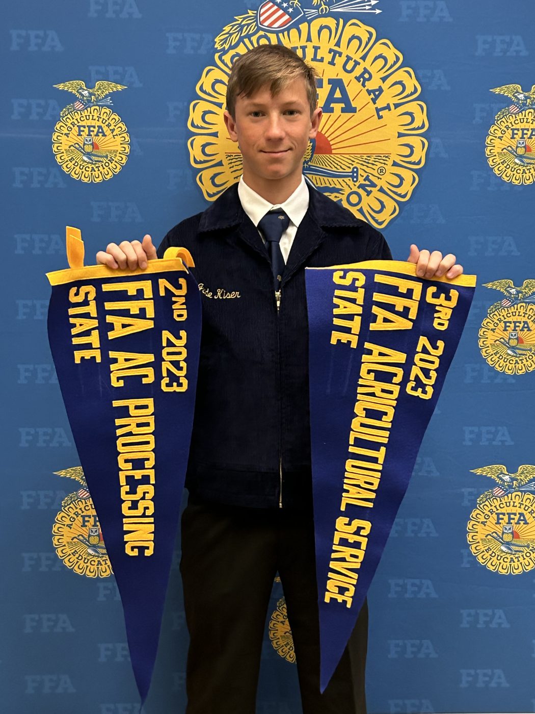 Jude holding his 2023 FFA State pennants for Agricultural Service and Ag Processing